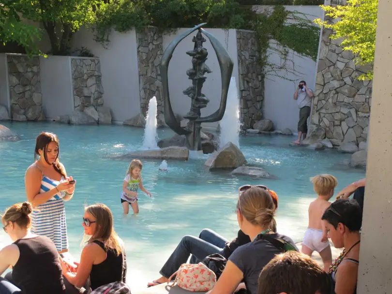 Families relaxing and wading at the fountain on a summer day
