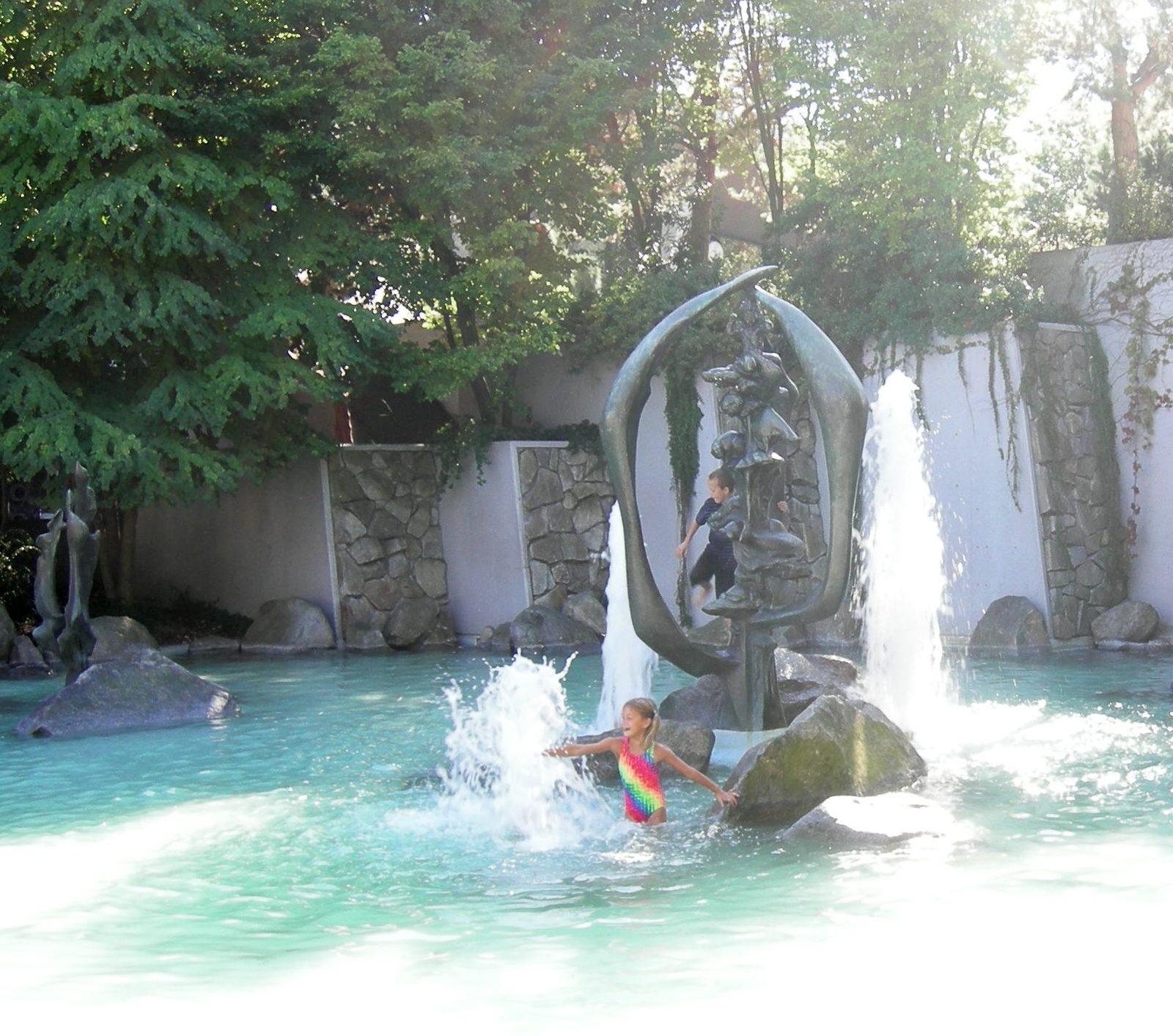 Children playing among the boulders and sculpture in the wading pool