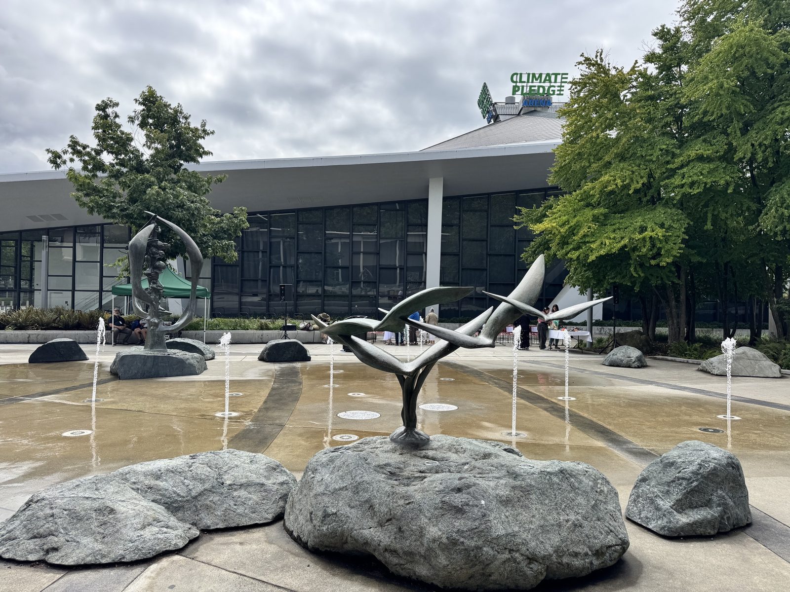 The Fountain of Creation plaza at Seattle Center, with both bronze sculptures and Climate Pledge Arena beyond