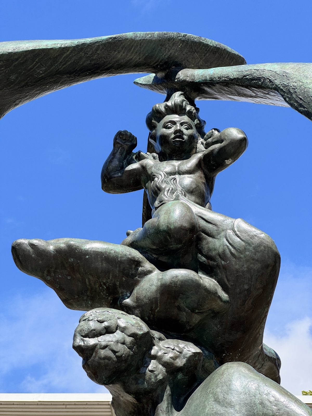 Detail of the top of Evolution of Man — figures reaching upward between sweeping bronze arcs