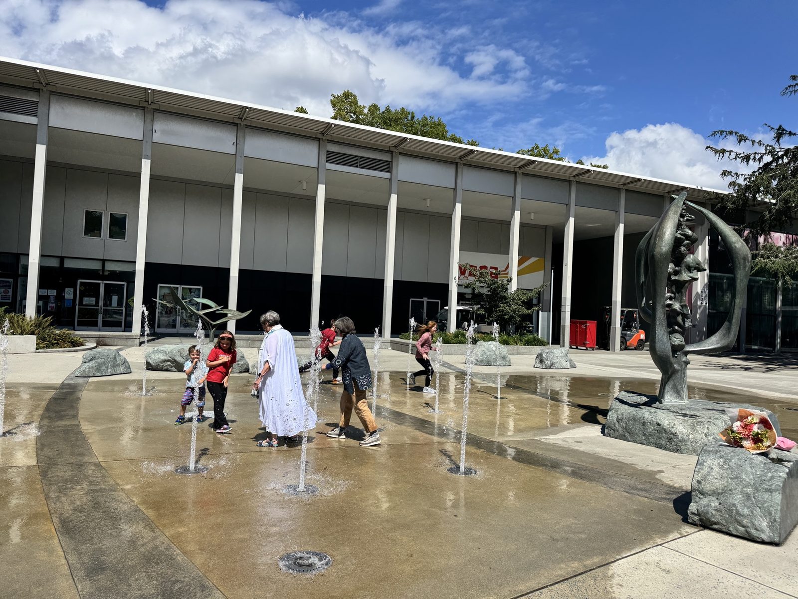 Families walking through the water jets on the new plaza