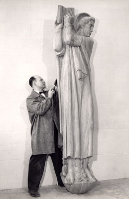 DuPen standing next to a tall carved wooden saint figure